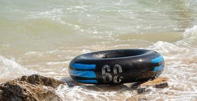 Nahaufnahme des schwarzen aufblasbaren Rings oder Gummirings auf dem Felsen am Meeresstrand foto