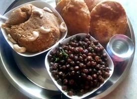 Suji Halwa Puri oder Shira Poori Frühstück, serviert in einem Teller und einer Schüssel. selektiver Fokus foto