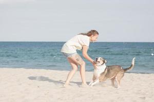 Frau spielt mit Hund am Strand foto