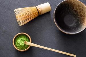 grüner Matcha-Tee, der auf einem schwarzen Steintisch zubereitet wird foto