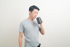 junger asiatischer mann, der kaffeetasse hält foto