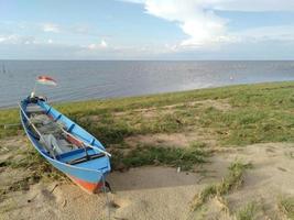 kleines Schiff am Strand mit einer rot-weißen Flagge am Heck foto