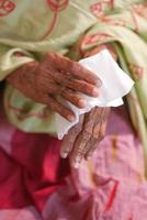Ältere Frauen, die seine Hände mit einem feuchten Tuch desinfizieren. foto