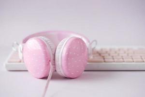 rosafarbener Kopfhörer auf der Tastatur auf Rosa. foto