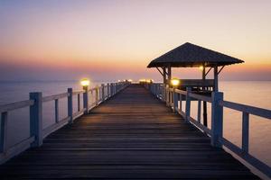 Blick auf die Holzbrücke, die bei Sonnenuntergang ins Meer ragt foto