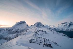 segla berg auf schneebedecktem hügel mit buntem himmel bei sonnenaufgang auf der insel senja foto