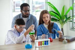 Studenten mischen Chemikalien in Bechergläsern. begeisterter lehrer erklärt kindern chemie, chemiestudent zeigt dem naturwissenschaftsunterricht ein neues experiment foto