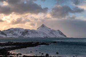 Schneegebirge mit Vögeln, die abends an der Küste fliegen foto