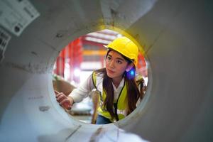 Vorarbeiterin oder Arbeiterin arbeitet auf dem Werksgelände und überprüft Maschinen oder Produkte vor Ort. ingenieur oder techniker, der material oder maschine in der anlage überprüft. Industrie und Fabrik. foto