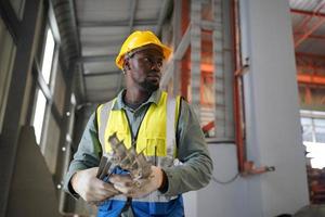 Männer-Wirtschaftsingenieur, der einen Schutzhelm trägt, während er in einer Schwerindustriefabrik steht. die Wartung von Arbeiten an Industriemaschinen und die Einrichtung des Sicherheitssystems in der Fabrik.