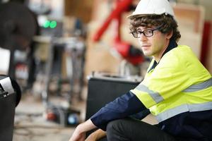 ingenieur, der das bedienfeld überprüft und einen neuen automatischen roboterarm und eine betriebssteuerungsmaschine in der fabrik einlernt. foto