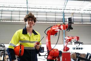 ingenieur, der das bedienfeld überprüft und einen neuen automatischen roboterarm und eine betriebssteuerungsmaschine in der fabrik einlernt. foto