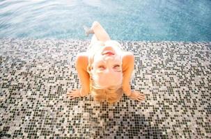 junge frau, die eine sonne genießt, schlankes junges mädchenmodell im weißen bikini am pool. foto