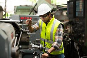 Arbeiter arbeiten auf dem Werksgelände und überprüfen die Maschine in der Produktlinie oder die Produkte vor Ort. ingenieur oder techniker, der material oder maschine in der anlage überprüft. Industrie und Fabrik. foto