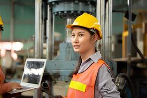 Arbeiterinnen arbeiten auf dem Werksgelände und überprüfen die Maschine in der Produktlinie oder die Produkte vor Ort. ingenieur oder techniker, der material oder maschine in der anlage überprüft. Industrie und Fabrik. foto