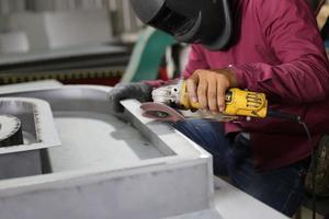 Schweißer verwendet Schleifstein auf Stahl in Fabrik mit Funken, Schweißprozess in der Industriewerkstatt, Hände mit Instrument im Rahmen. foto