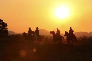 Silhouette Cowboy zu Pferd vor einem wunderschönen Sonnenuntergang, Cowboy und Pferd im ersten Licht, Berg, Fluss und Lebensstil mit natürlichem Lichthintergrund foto