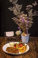 Gegrilltes Steak mit Pommes Frites und Gemüse, serviert auf einem Holztisch foto