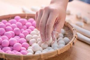 Eine asiatische Frau macht Tang Yuan, Yuan Xiao, traditionelle chinesische Reisknödel in Rot und Weiß für das neue Mondjahr, Winterfest, Nahaufnahme. foto