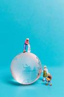 Miniaturmenschen reinigen Kristallkugel auf blauem Hintergrund foto
