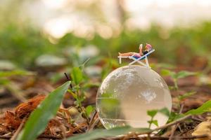Miniaturmenschen sonnen sich auf der Kristallkugel im Park foto
