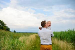 vater und mutter führen ihren einjährigen sohn an der hand. foto