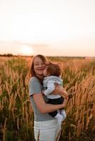 Eine Mutter geht mit ihrer kleinen Tochter im Arm über das Feld. foto