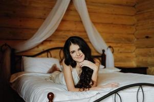 Schönes Mädchen in Penuar, das auf dem Bett liegt foto