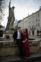 Porträt eines schönen lächelnden Liebespaares, das in der Nähe eines Brunnens im Freien in der Stadt sitzt. hübscher junger Mann und Frau. foto