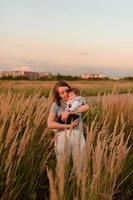 Eine Mutter geht mit ihrer kleinen Tochter im Arm über das Feld. foto