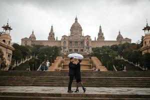 junges schönes liebevolles hispanisches paar geht während des regens unter einem regenschirm spazieren. foto