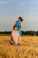 Erwachsener Bauer und Ehefrau verbringen Zeit auf dem Feld. der mann sitzt. Eine Frau steht neben ihm und umarmt ihn. Eine Frau küsst ihren Mann auf den Kopf. foto