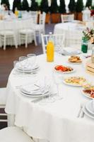 In einem weißen Hochzeitspavillon stehen runde, mit blauen Stoffen gedeckte Esstische foto