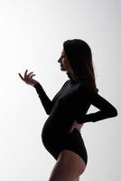 junge schöne schwangere frau im schwarzen bodysuit und im hut. foto