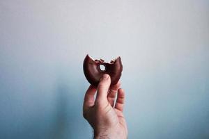 Hand mit einem Schokoladenkrapfen foto