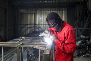 Schweißer verwendet Schleifstein auf Stahl in Fabrik mit Funken, Schweißprozess in der Industriewerkstatt, Hände mit Instrument im Rahmen. foto