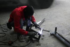 Schweißer verwendet Schleifstein auf Stahl in Fabrik mit Funken, Schweißprozess in der Industriewerkstatt, Hände mit Instrument im Rahmen. foto