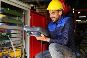 ingenieur, der das bedienfeld überprüft und einen neuen automatischen roboterarm und eine betriebssteuerungsmaschine in der fabrik einlernt. foto