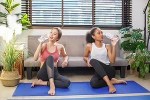 Lifestyle-Porträt von zwei lustigen jungen Freunden auf Sportbekleidung haben Spaß und trinken Wasser nach dem Yoga. Partystimmung zu Hause. Internationaler Frauentag. glückliche junge frauen, die lächeln. foto