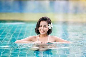junge frau genießt und entspannt sich am pool. Schlankes junges Mädchenmodell im weißen Bikini am Pool. foto