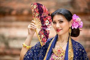 junge asiatische frauen in traditioneller kleidung im boot und rosa lotusblumen im teich. schöne mädchen in traditioneller tracht. thailändisches mädchen im retro-thailändischen kleid, thailändisches mädchen im traditionellen kostüm foto