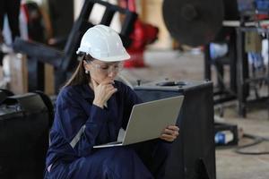 Diverse multikulturelle Ingenieure und Arbeiter der Schwerindustrie in einheitlichen Check-Automatik-Roboterarmen für die Verwendung in der Fabrik. Weiblicher Industrieunternehmer verwendet einen Tablet-Computer. foto