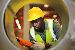 Männer-Wirtschaftsingenieur, der einen Schutzhelm trägt, während er in einer Schwerindustriefabrik steht. die Wartung von Arbeiten an Industriemaschinen und die Einrichtung des Sicherheitssystems in der Fabrik. foto