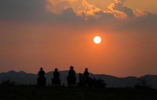 Silhouette Cowboy zu Pferd vor einem wunderschönen Sonnenuntergang, Cowboy und Pferd im ersten Licht, Berg, Fluss und Lebensstil mit natürlichem Lichthintergrund foto