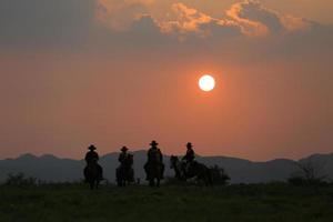 Silhouette Cowboy zu Pferd vor einem wunderschönen Sonnenuntergang, Cowboy und Pferd im ersten Licht, Berg, Fluss und Lebensstil mit natürlichem Lichthintergrund foto