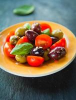 marinierte schwarzgrüne Oliven mit Kirschtomaten-Basilikum-Blattsalat. foto