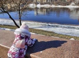 Ein kleines Mädchen blickt nach der Eisdrift im Frühling auf den Fluss. foto