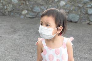 3 Jahre altes asiatisches Mädchen, das während des Coronavirus covid-19 eine weiße Gesichtsschutzmaske trägt. foto