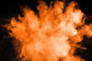 abstrakte orange pulverexplosion auf schwarzem hintergrund. bewegung des orangen staubspritzers einfrieren. foto