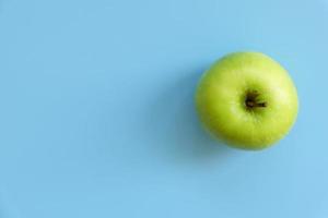 eine reife grüne Apfelfrucht isoliert auf blauem Hintergrund mit Kopierplatz für Text. Ansicht von oben.
